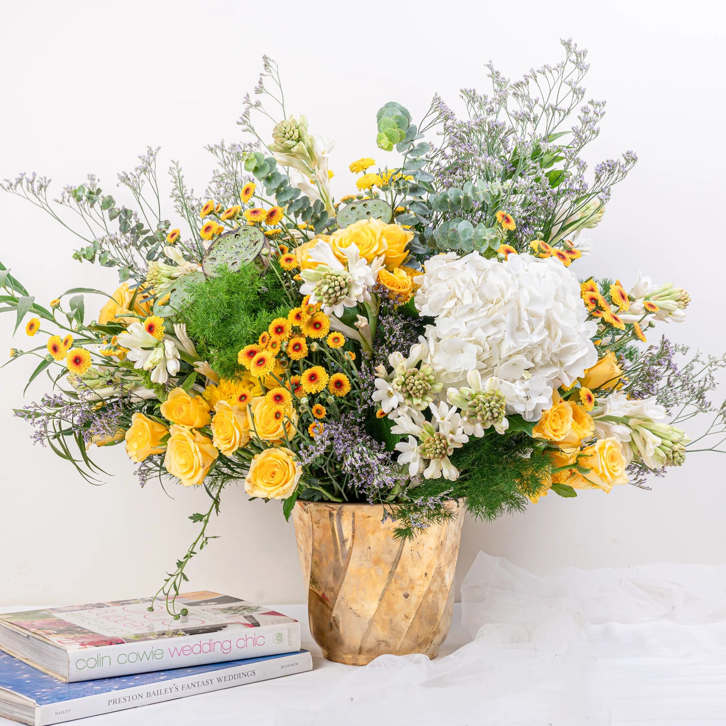 Citrus & Ivory luxury centerpiece with yellow roses, white hydrangea, gerberas, tuberose and eucalyptus in gold geometric vase by House of Mograa
