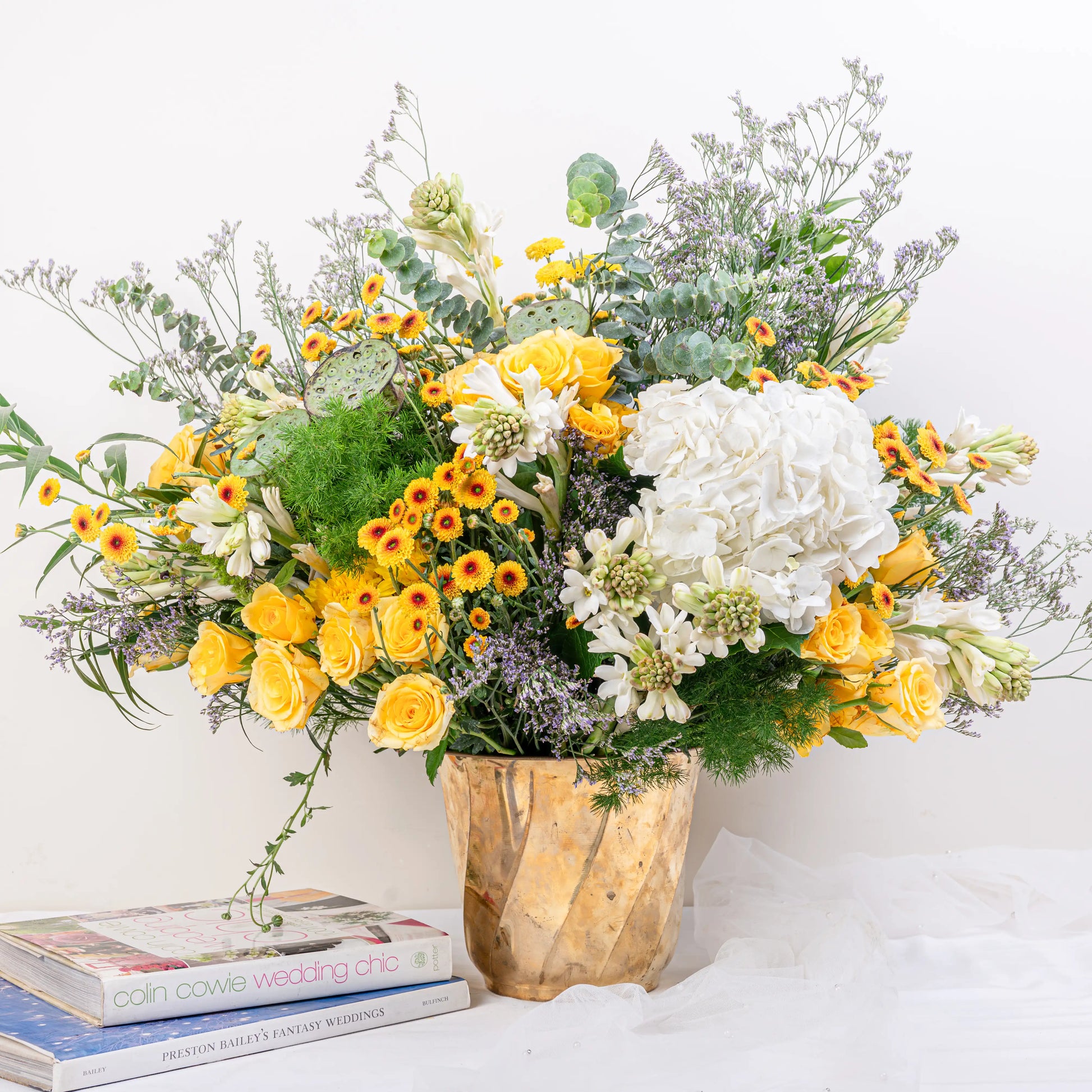 Citrus & Ivory luxury centerpiece with yellow roses, white hydrangea, gerberas, tuberose and eucalyptus in gold geometric vase by House of Mograa