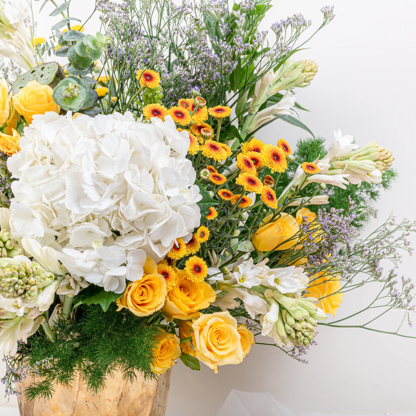 Citrus & Ivory luxury centerpiece with yellow roses, white hydrangea, gerberas, tuberose and eucalyptus in gold geometric vase by House of Mograa