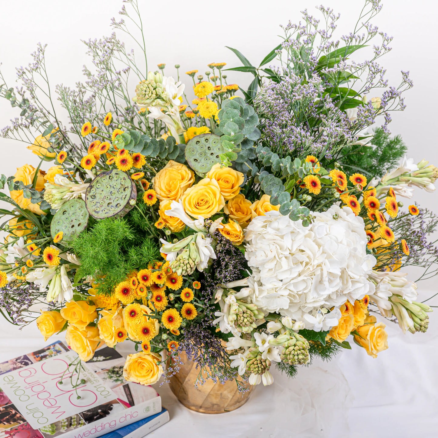 Citrus & Ivory luxury centerpiece with yellow roses, white hydrangea, gerberas, tuberose and eucalyptus in gold geometric vase by House of Mograa